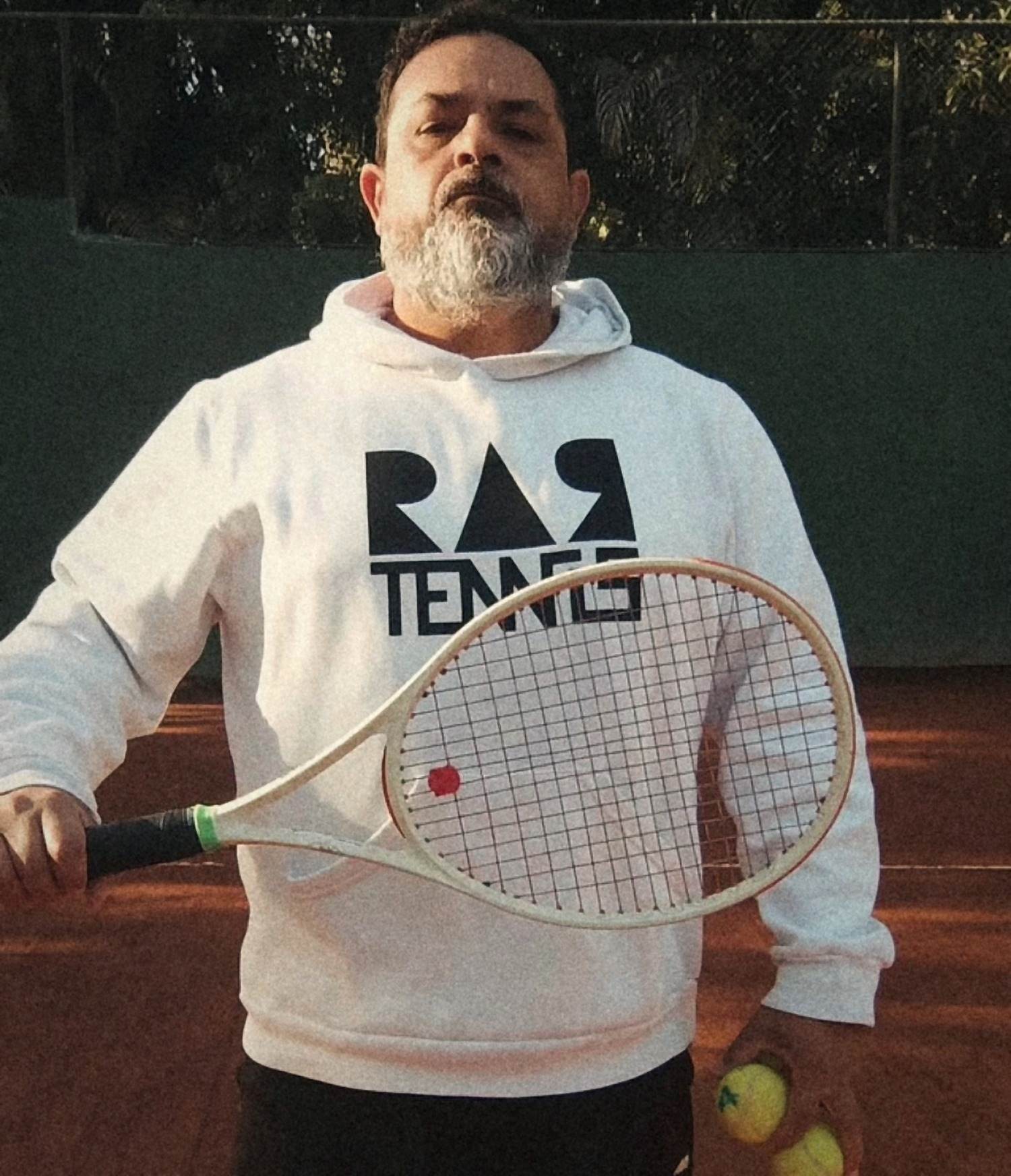 Rodrigo Aranha, professor da RAR Tennis, segurando a raquete na quadra de saibro.